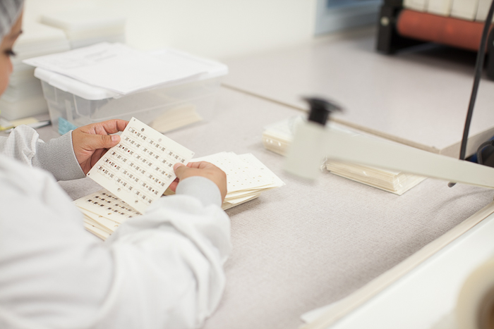 une assembleuse inspecte une feuille d'interrupteurs à dôme en métal